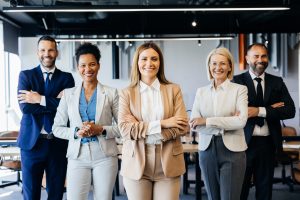 A team of business professionals stand united in an office environment, arms crossed to represent strength, teamwork, and confidence